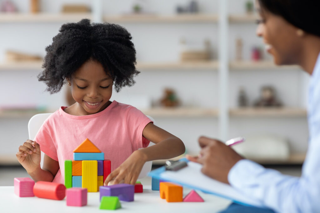 Child development specialist observing cheerful child preschooler